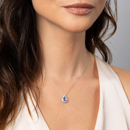A woman wearing a silver teardrop halo pendant at the collarbone