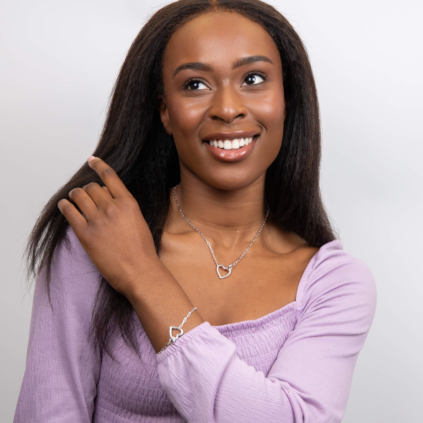 A woman wearing the Beginnings Heart Connection Chain Bracelet with the matching necklace.