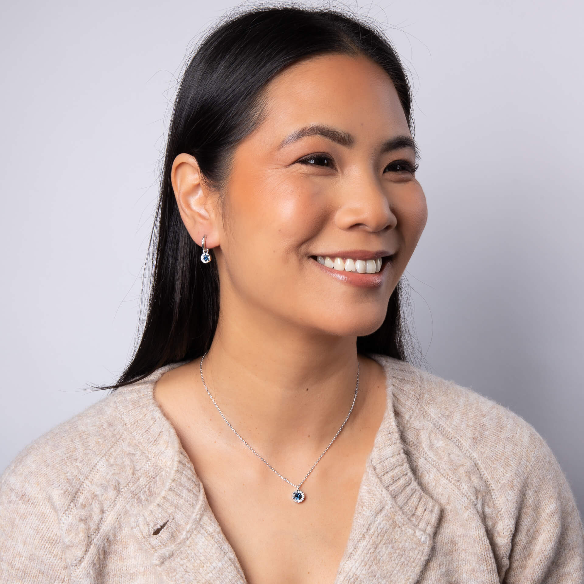A woman wearing the Laura Ashley Bowen Star Crystal Necklace with matching pieces.
