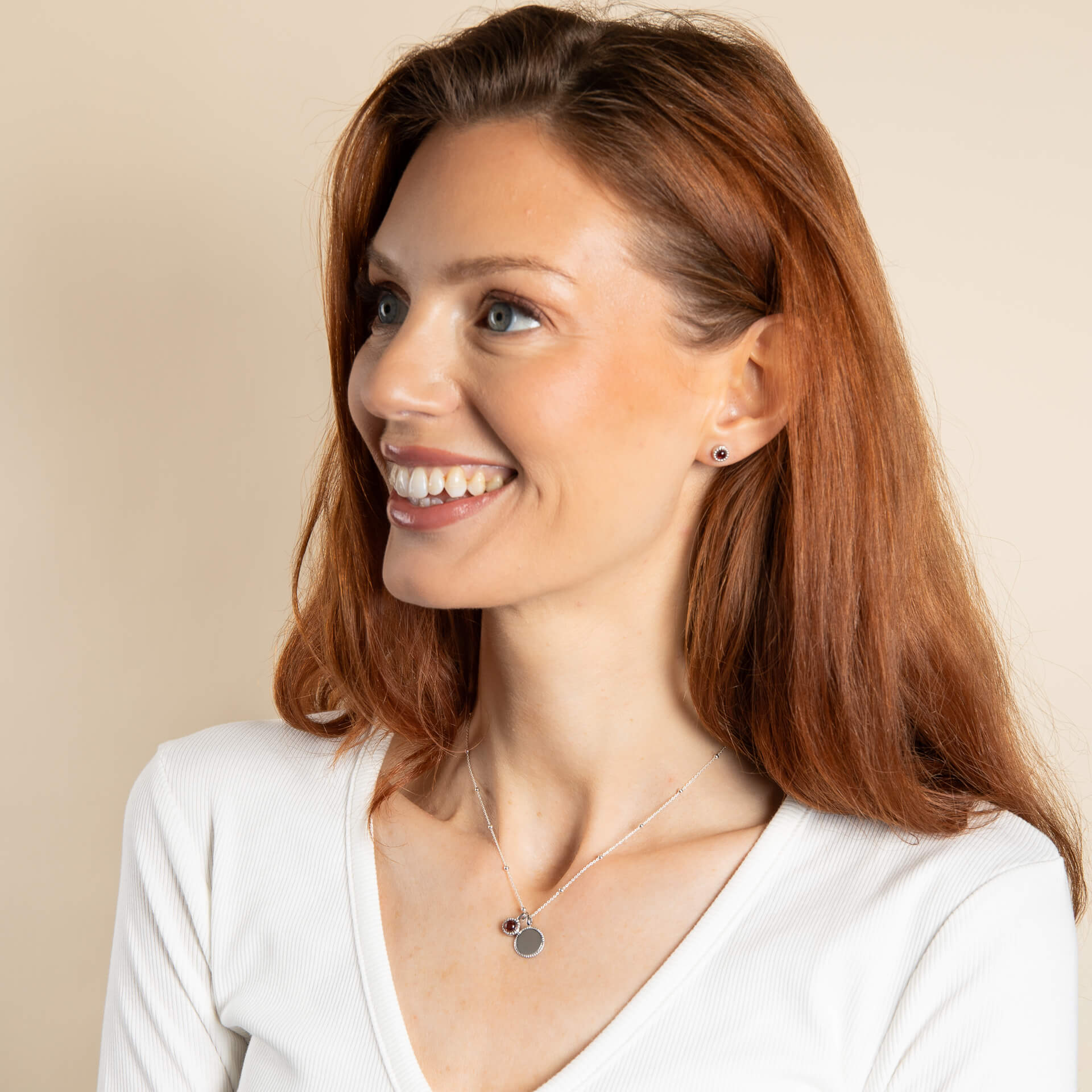 A woman wearing the Beginnings milgrain birthstone studs with a matching pendant.