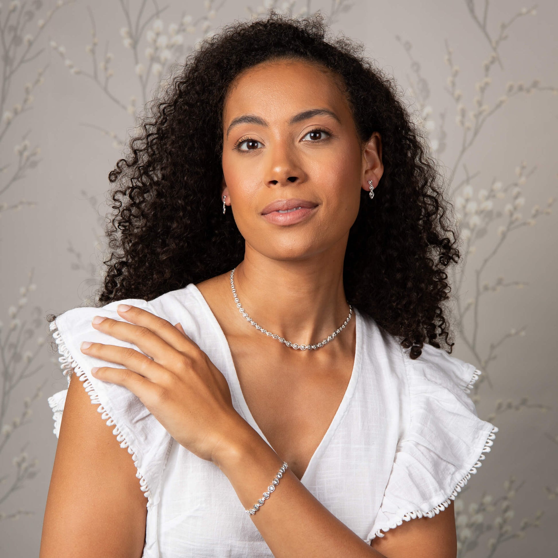 A woman wearing the Laura Ashley Tulip Chain Bracelet with matching pieces.