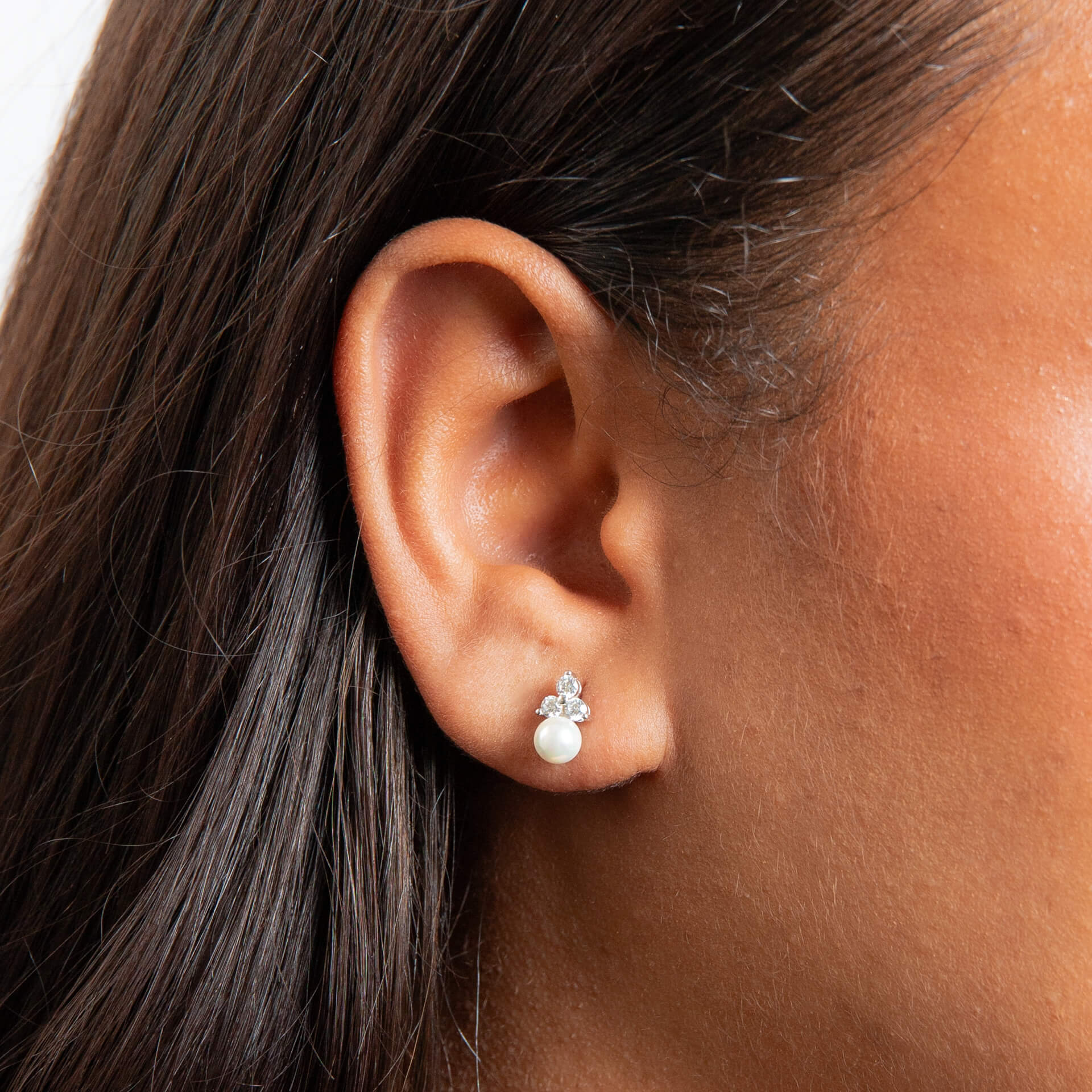 A woman wearing the Beginnings shell pearl and zirconia stud earrings.