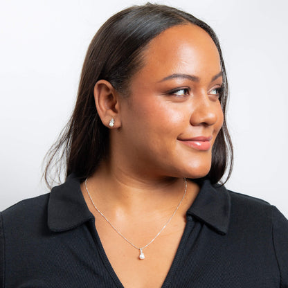 A woman wearing the Beginnings shell pearl and zirconia stud earrings with matching pieces.