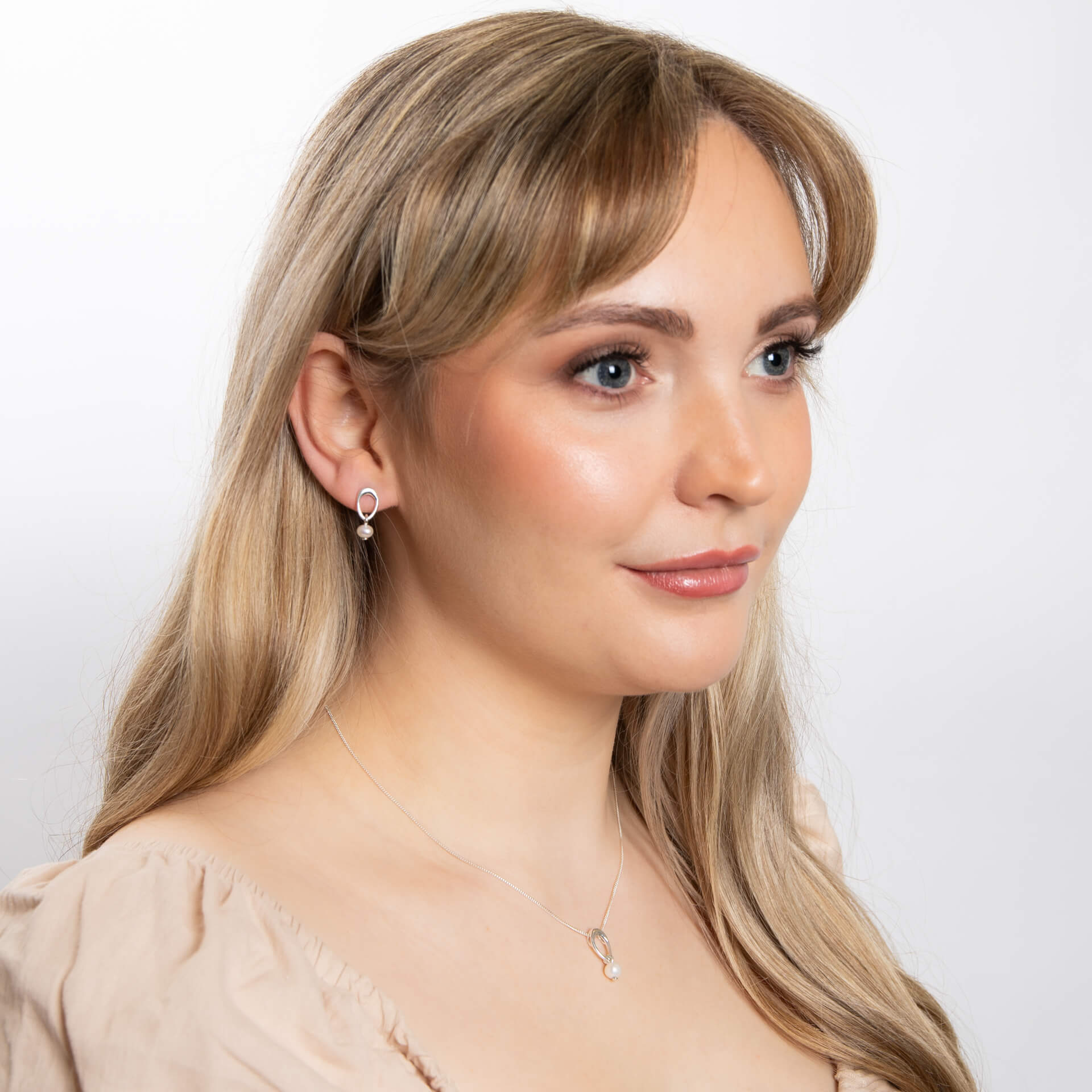 A woman wearing the Beginnings organic oval pearl pendant with matching pieces.