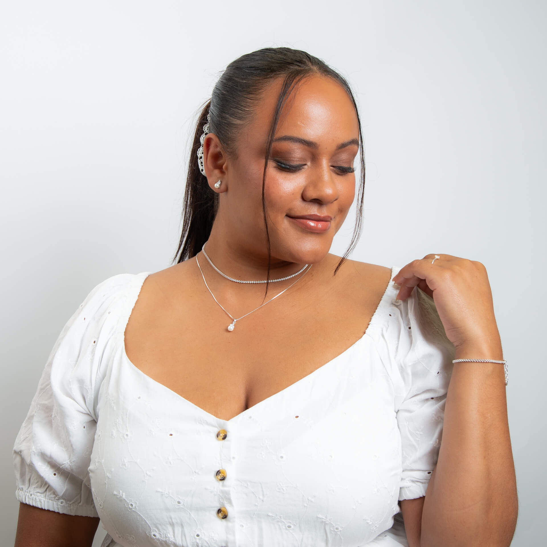 The Beginnings shell pearl and zirconia stud earrings worn with other pieces.