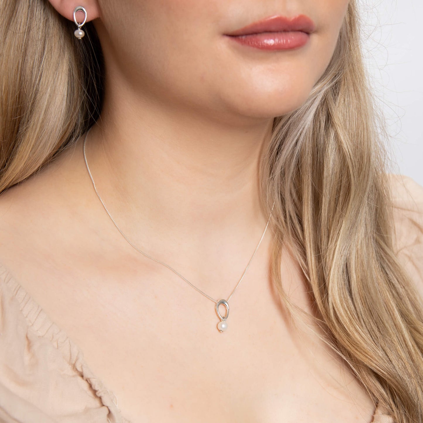 A woman wearing the Beginnings organic oval pendant with a freshwater pearl drop.